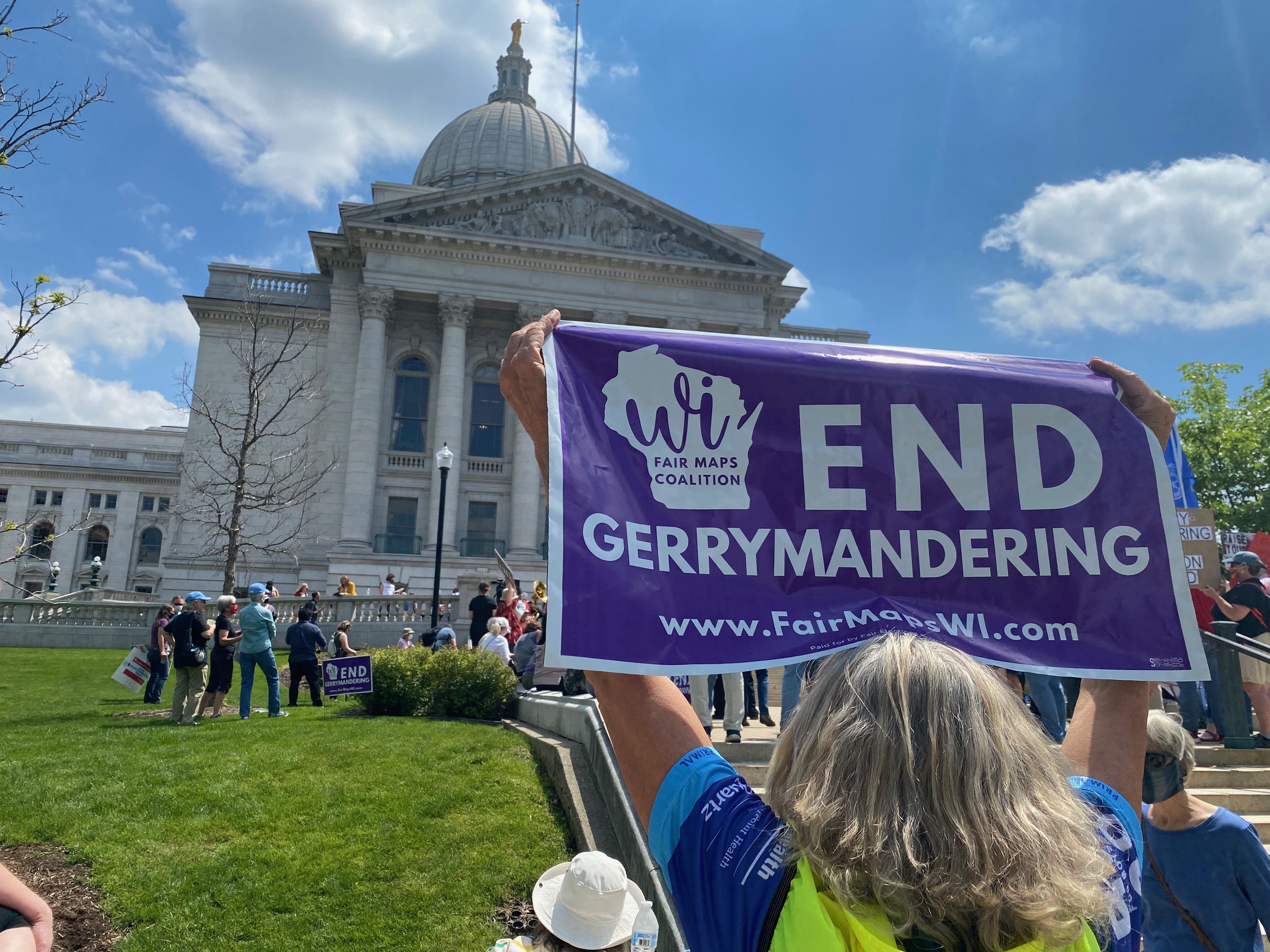 an "end gerrymandering" flag being held up in front of the Wisconsin Capitol